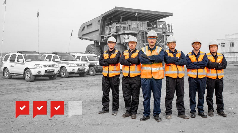 mining professionals stand in front of line up of mining machinery