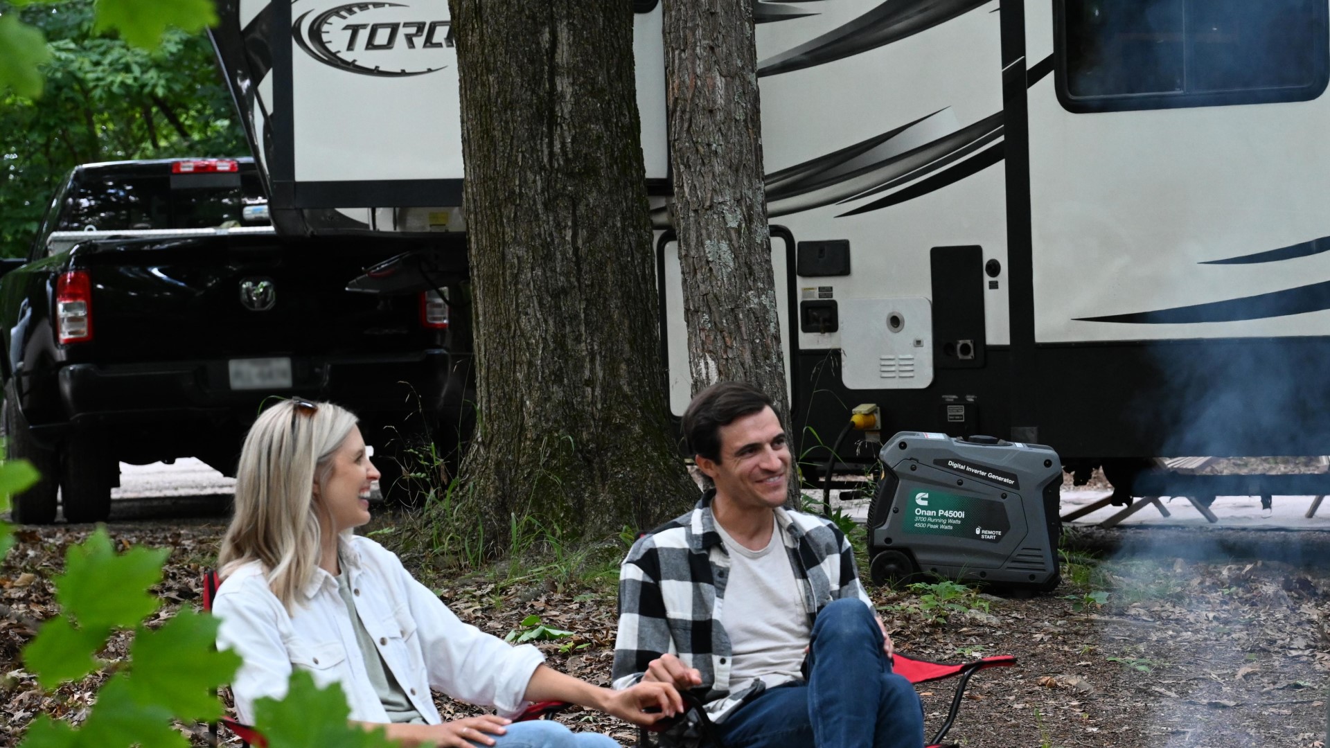 People around a camp fire with trailer in the background