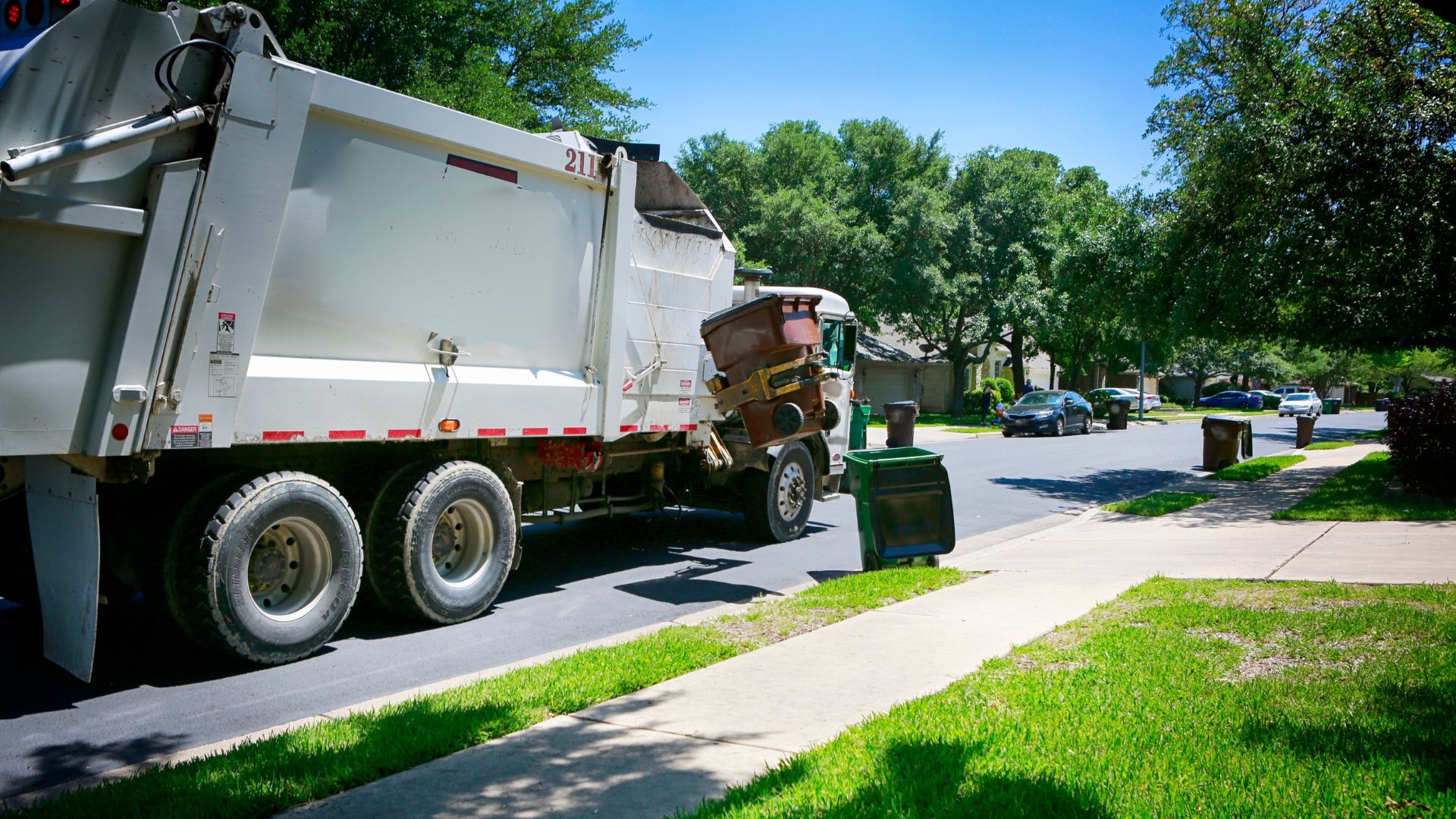 garbage truck picking up trash in neighborhood