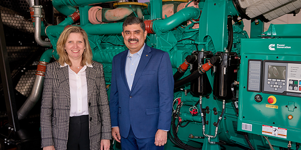 Leaders smiling in front of generator