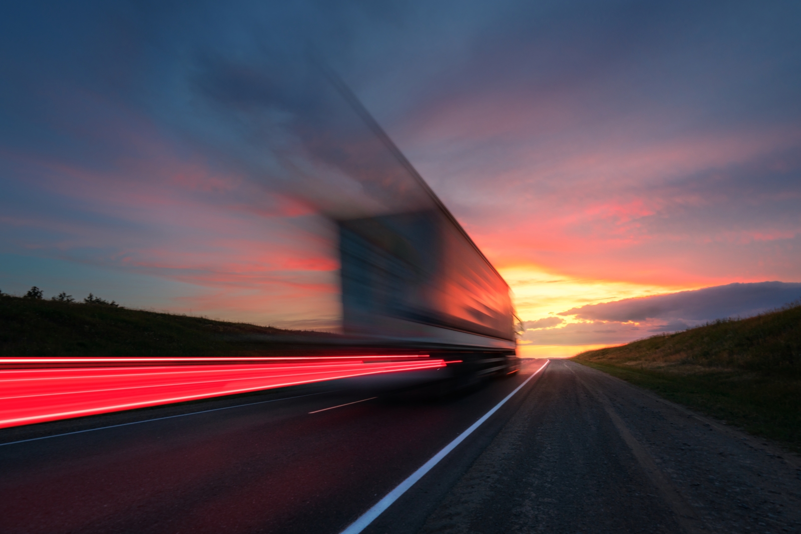 A long exposure of a truck driving past at sunset