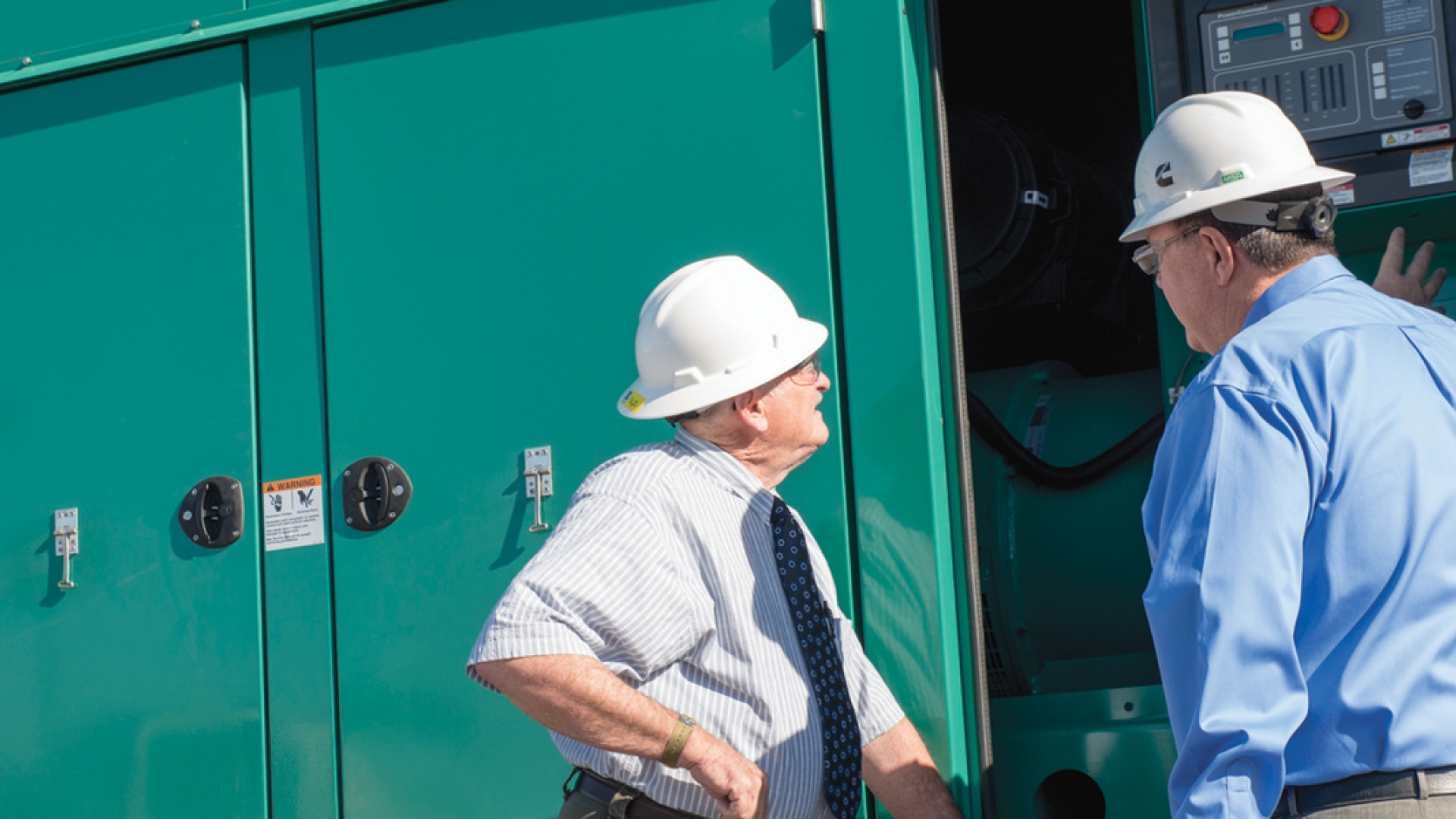 men talking next to cummins generator