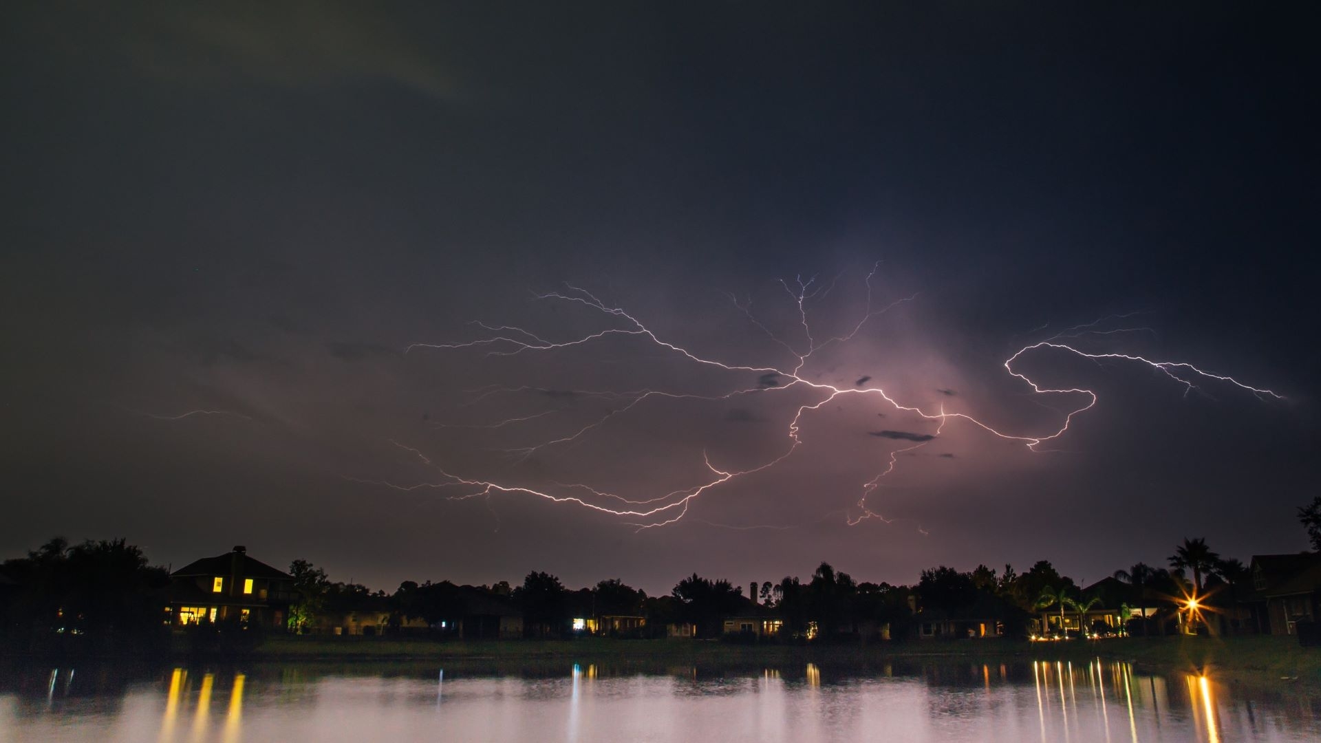 lightning storm over lakeside houses