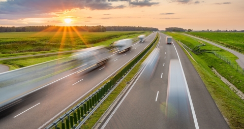 four lane highway at sunset with semi trucks driving on them in a blur