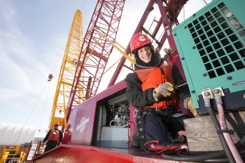 woman wearing cold weather gear and a cummin red hard hat on a construction site