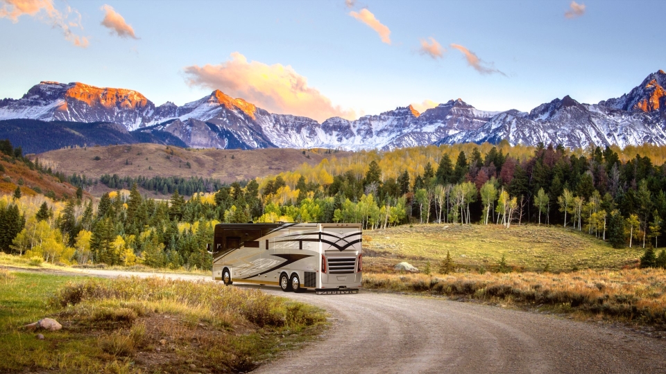 Rv going down a hill with mountains in the background