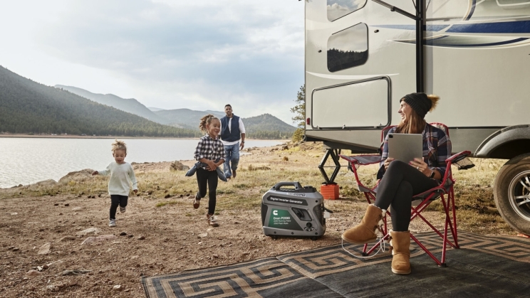 family enjoying rv camping near water and mountains with a cummins portable generator