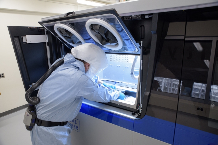 Cummins employee Devin Hunter cleans one of the company’s 3D printers at the Cummins Technical Center in Columbus, Indiana, before another round of printing. Metal 3D printers could revolutionize manufacturing.