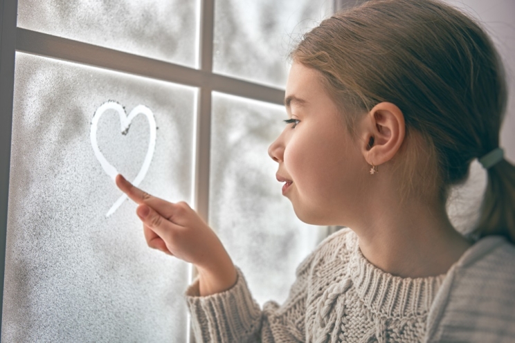 Girl at frozen window on a snowy day 