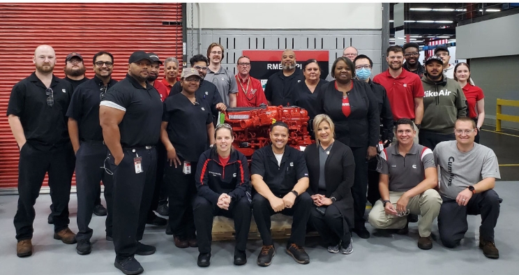 RMEP employees standing next to Cummins engine