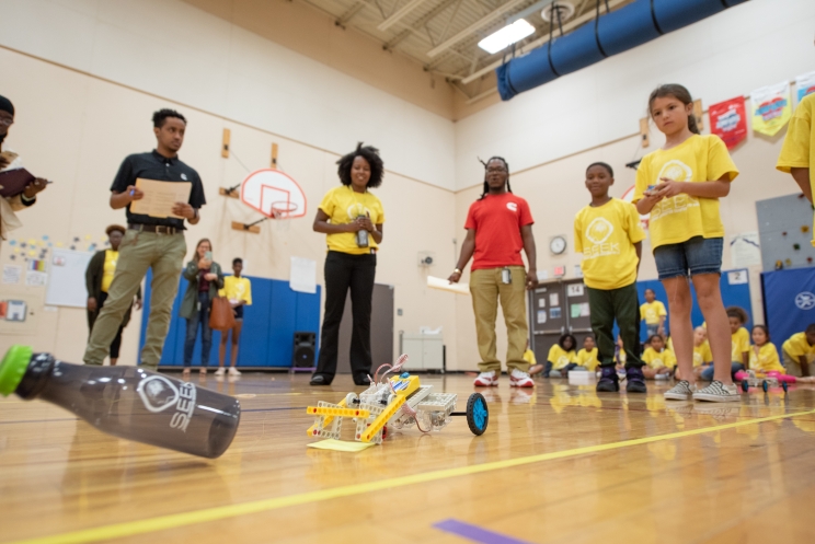 SEEK third grader controls her team's robot through the obstacle course, as Cummins employees, SEEK mentors and others watch in amazement.