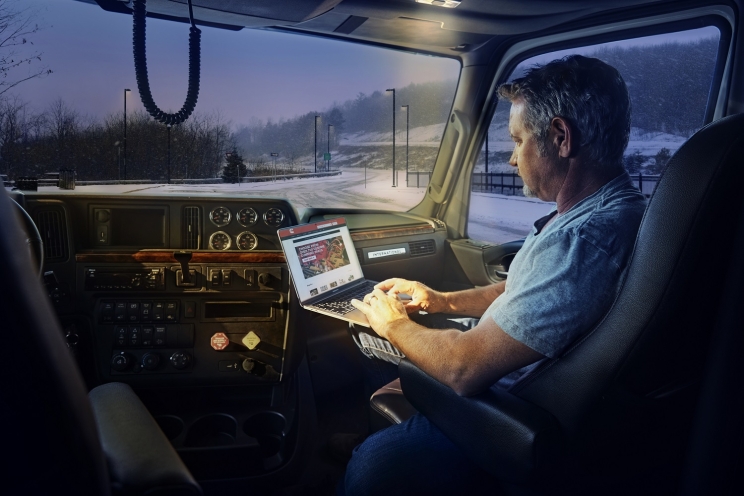 A truck passenger uses shop.cummins.com on a laptop inside the cab.