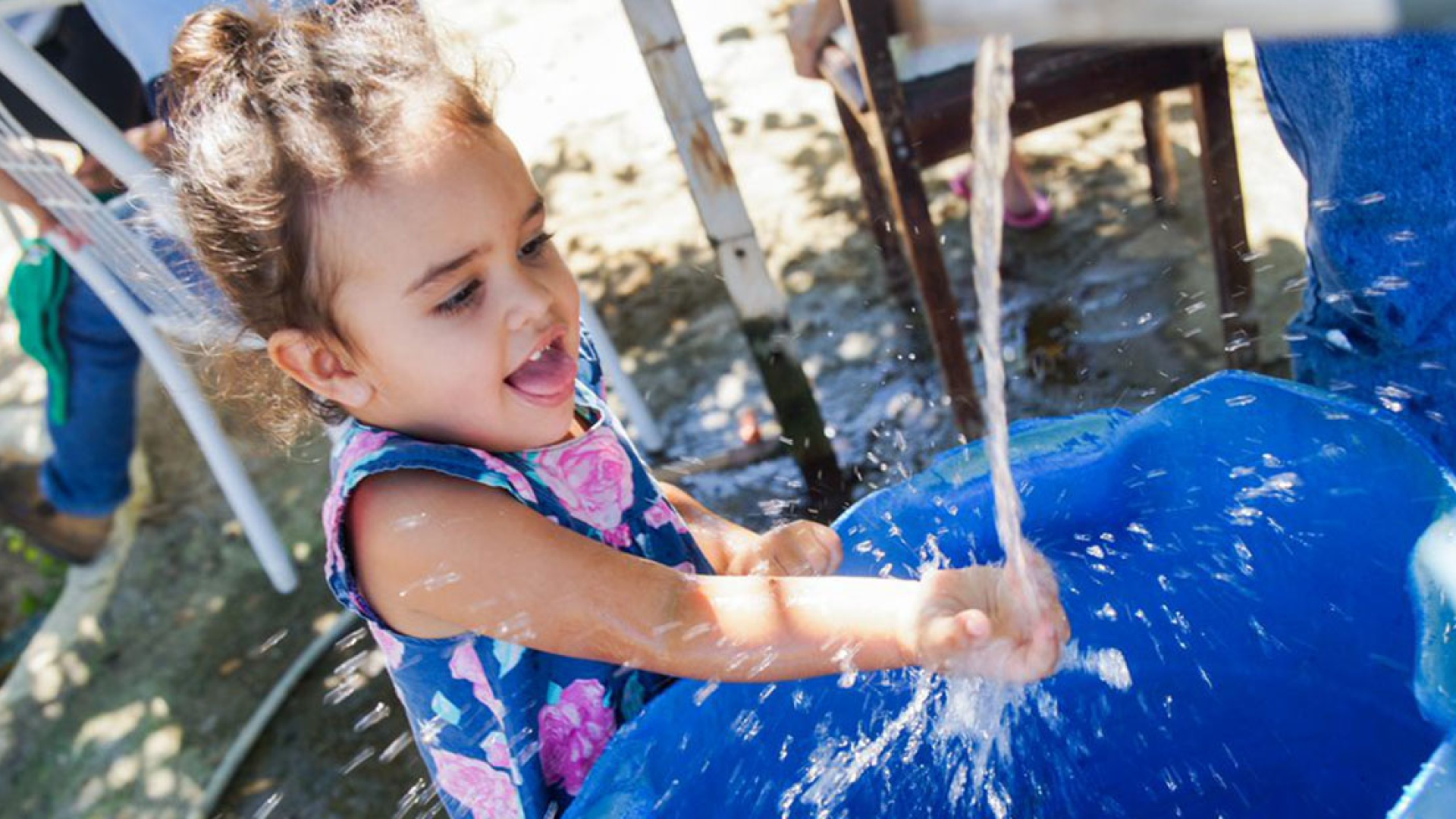 Child reaching hand out receiving clean water