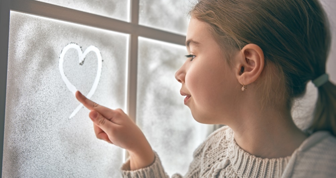 Girl at frozen window on a snowy day 