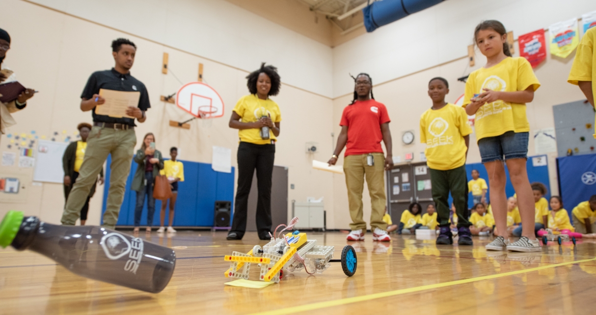SEEK third grader controls her team's robot through the obstacle course, as Cummins employees, SEEK mentors and others watch in amazement. SEEK third grader controls her team's robot through the obstacle course, as Cummins employees, SEEK mentors and others watch in amazement.