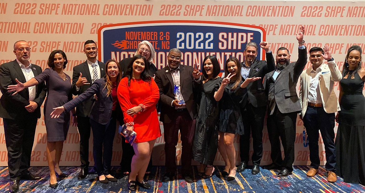 Employees in front of SHPE awards banner