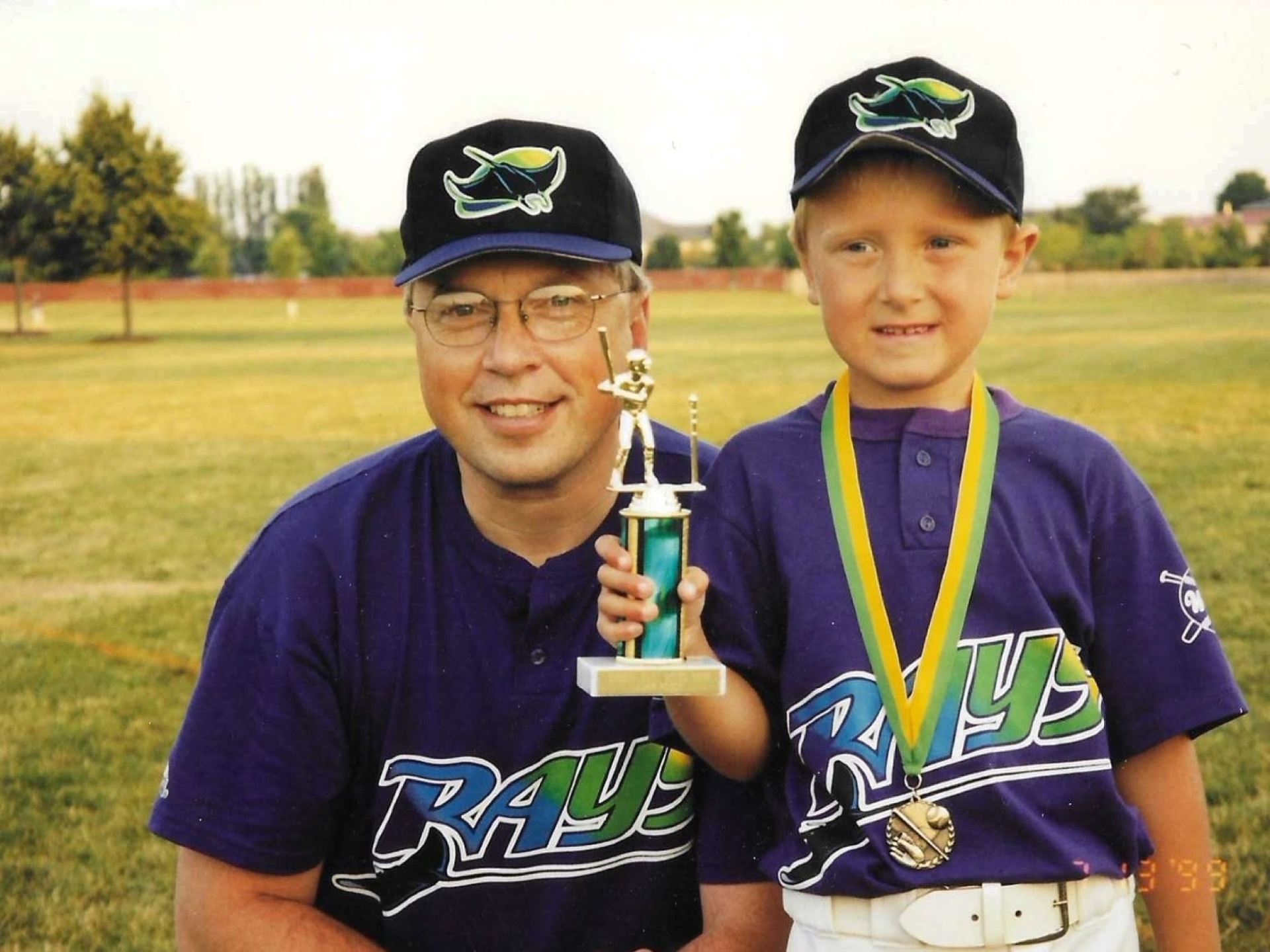 father and son with little league baseball trophy