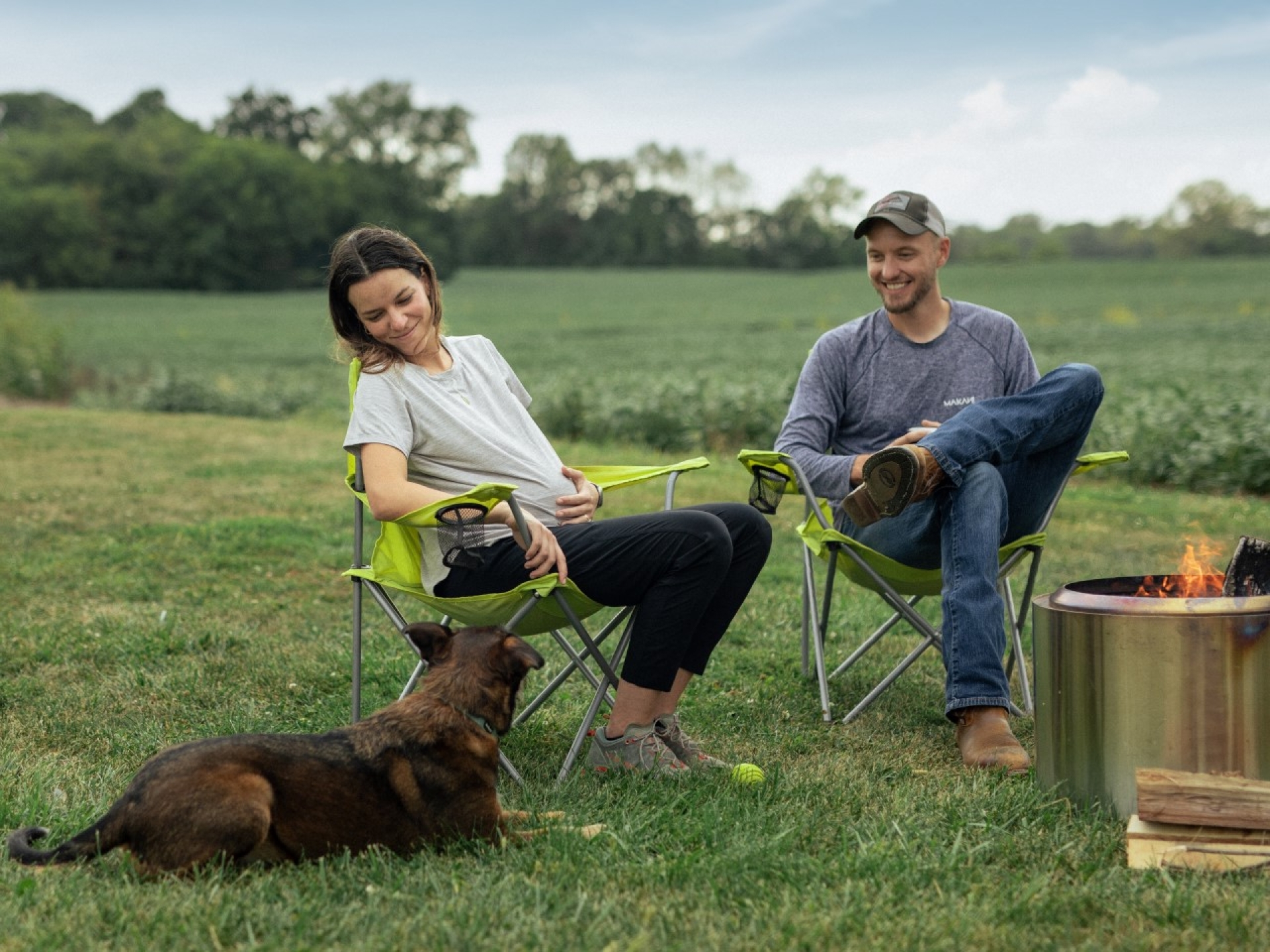 couple siting next to camp fire with dog