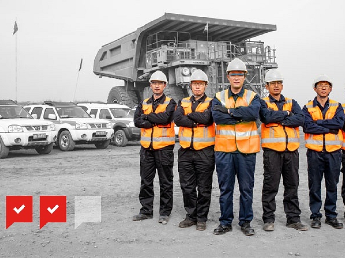 mining professionals stand in front of line up of mining machinery