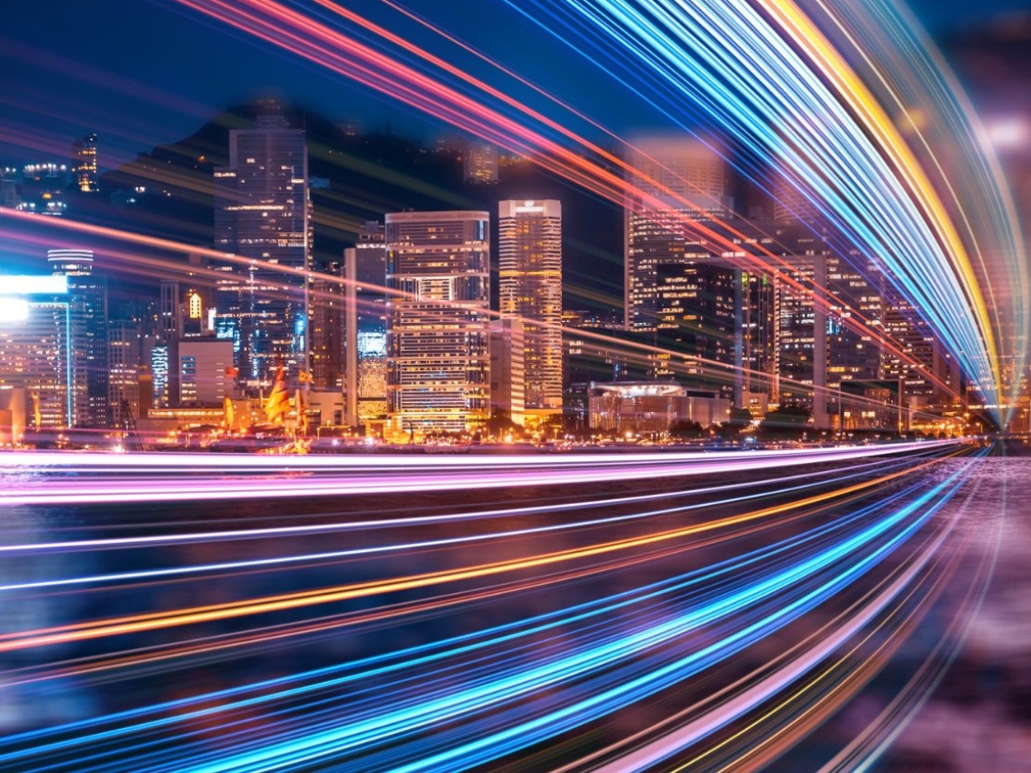 streaking lights from moving cars with city buildings in background