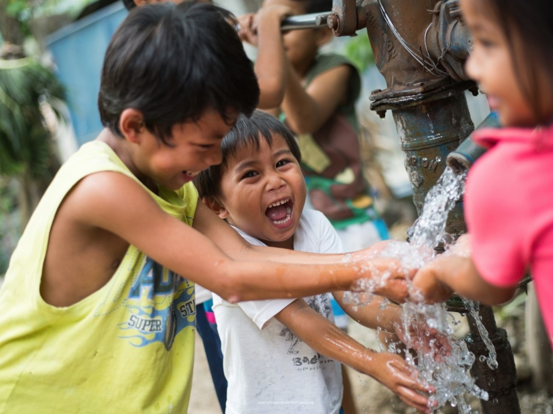 kids around outside water faucet in Philippines
