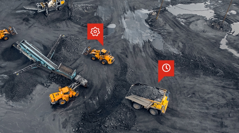 overhead view of large mining vehicles in action with red gear and clock icons