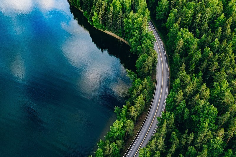 highway alongside forest and lake