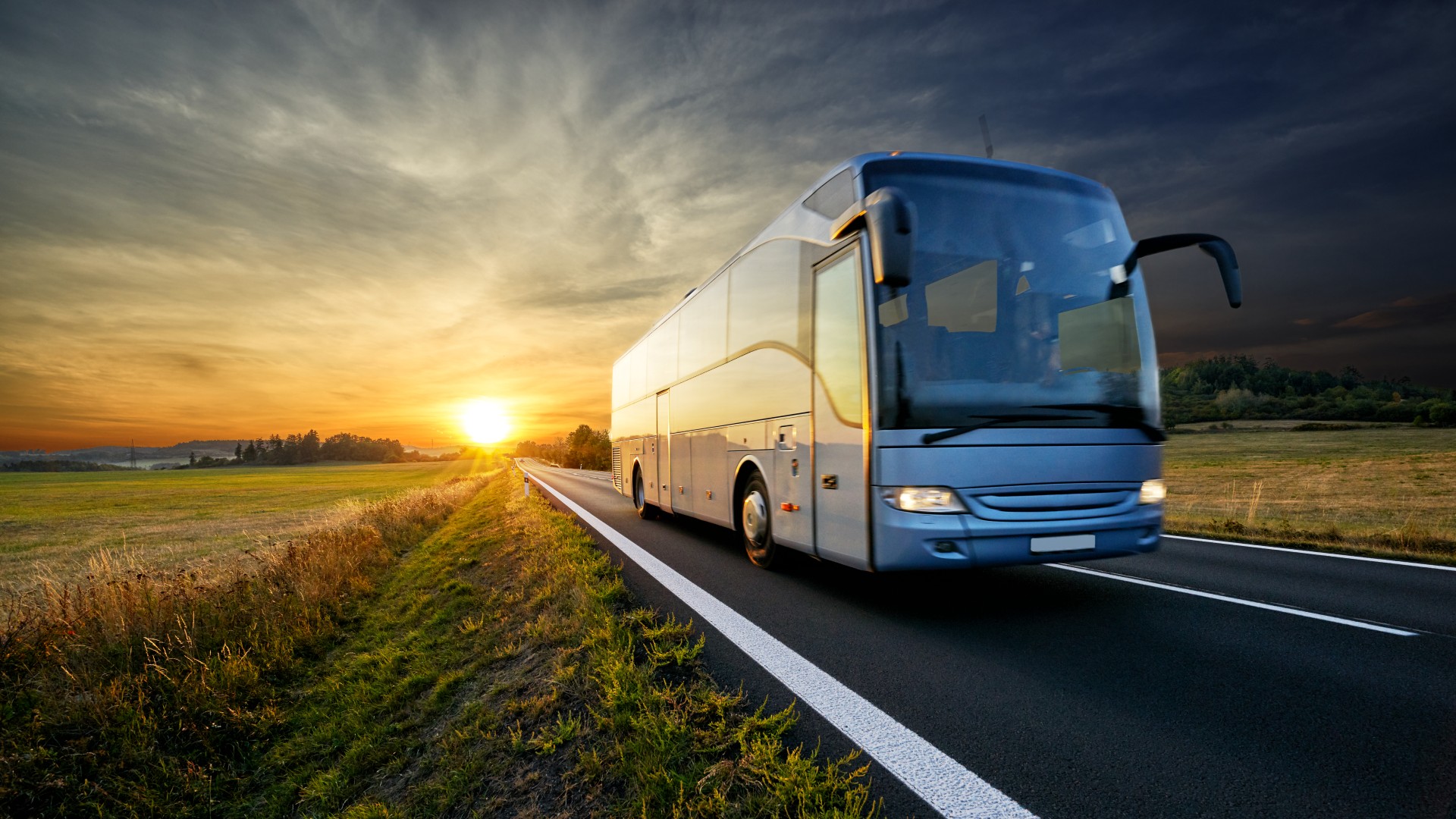 Bus driving away from the sun while it's setting