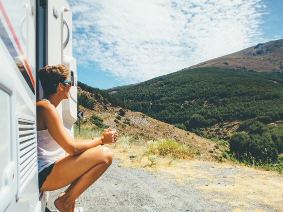 Woman drinking coffee outside her RV looking at a mountain